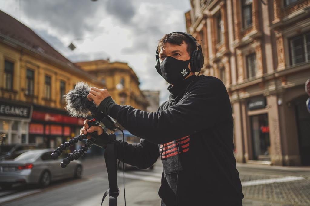 Person in street using field recording equipment.